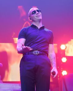 a man in sunglasses standing on stage with his arms folded out and looking to the side