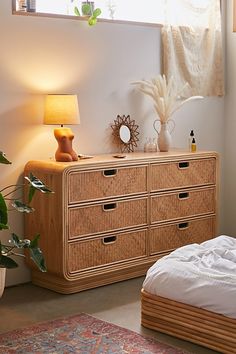 a bedroom scene with focus on the dresser and bed side table, which has a plant next to it