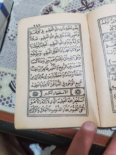 an open book with arabic writing on it in someone's hand next to a doily