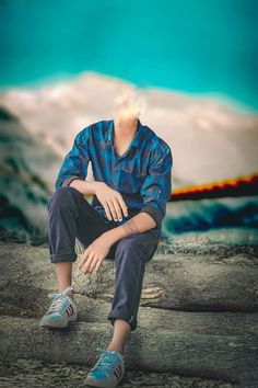 a young man sitting on top of a tree stump in front of a blue sky