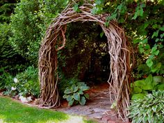 an arch made out of branches in the middle of a garden