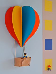 a hot air balloon hanging from the side of a wall with a paper bag attached to it