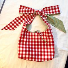 a red and white gingham bag with a green bow on it's neck