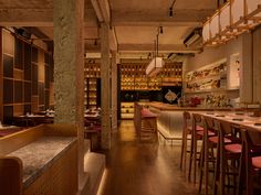 the interior of a restaurant with wooden tables and stools, red upholstered chairs