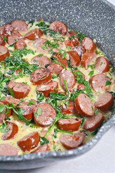 a pan filled with sausage and spinach on top of a stove