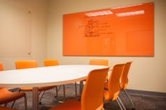 a conference room with orange chairs and a white table