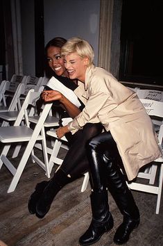 two women sitting on white chairs in front of each other