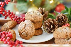 some cookies are sitting on a plate with berries and pine cones