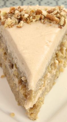 a piece of cake with white frosting and walnuts on top sitting on a plate