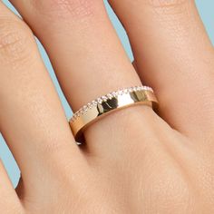 a woman's hand with a gold wedding band and diamond set on top of it