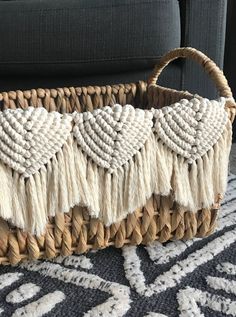 a woven basket sitting on top of a rug next to a black couch with white tassels