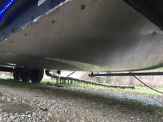 the back end of a boat on gravel and grass with blue lights in the background