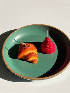 a green plate topped with a piece of fruit next to a strawberries on top of it