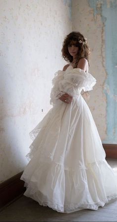 a woman in a white dress standing against a wall