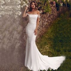 a woman in a wedding dress leaning against a stone wall