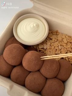 a container filled with lots of food next to a bowl of yogurt and chopsticks