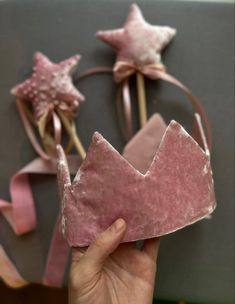 a hand holding up a pink crown made out of fabric with stars on the top