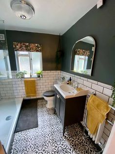 a bathroom with black and white tile flooring and yellow towels hanging on the rack