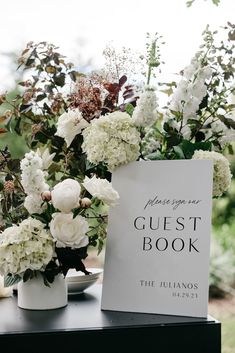 the guest book is sitting on top of a table with white flowers in vases