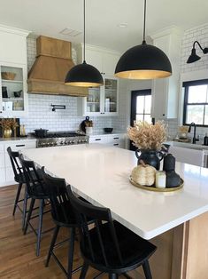 a large kitchen with black chairs and white counter tops, along with an island in the middle