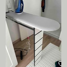 an ironing board sitting on top of a wooden floor next to a white cabinet