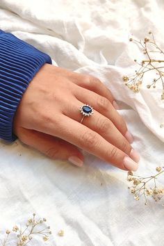 a woman's hand with a ring on it and flowers in the foreground