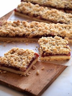 several pieces of dessert sitting on top of a wooden cutting board