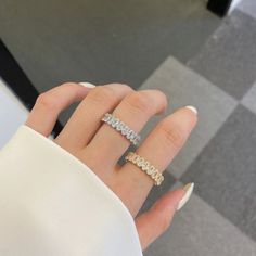 a woman's hand with a diamond ring on top of her finger and a checkered floor in the background