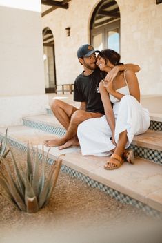 a man and woman are sitting on the steps in front of a building with an aloeve