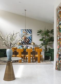 the dining room table is surrounded by yellow chairs and modern art on the wall behind it