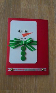 a christmas card with a snowman made out of buttons and green ribbon on it