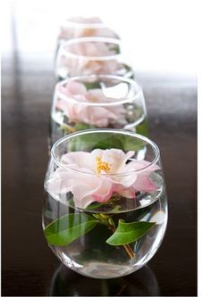 two vases filled with flowers on top of a wooden table next to each other