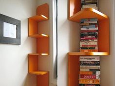 there are two shelves that have books on them in the same room, one is orange and the other is white