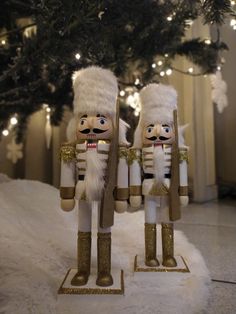 two nutcrackers standing next to each other in front of a christmas tree