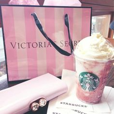 a starbucks drink with whipped cream in it next to a pink bag