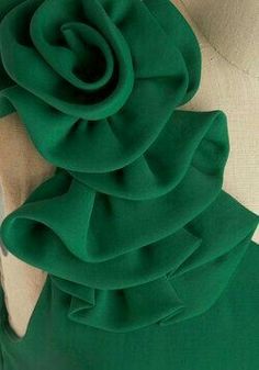 the back of a green dress with a flower on it