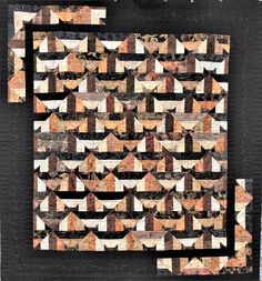 a quilted wall hanging on the side of a black board with brown and white designs