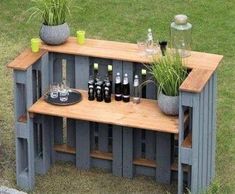 an outdoor bar made out of pallets with bottles and glasses on the top shelf