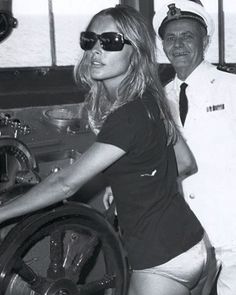 a black and white photo of two women in sailor's uniforms standing next to a steering wheel