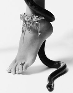 a black and white photo of a woman's foot with a snake on it