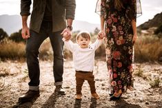 a little boy holding the hands of his parents