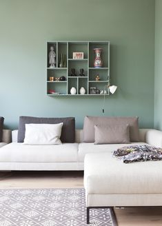 a living room with a white couch and some shelves on the wall above it that are filled with vases