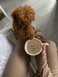 a person is holding a coffee cup with a dog on the other side and looking at them