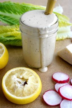 a mason jar filled with dressing next to sliced radishes and lettuce