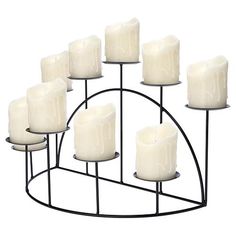 twelve white candles are arranged on a metal stand