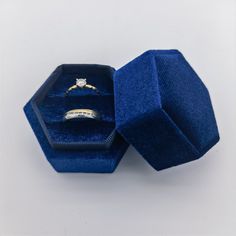 an open blue velvet ring box with a diamond in it