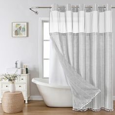 a white bath tub sitting under a window next to a shower curtain and rug on top of a hard wood floor