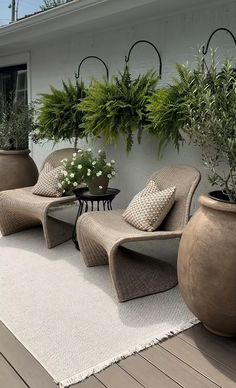 two chairs and a table on a deck with potted plants