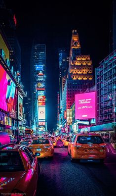 a city street filled with lots of traffic and tall buildings in the background at night