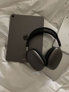 an apple ipad and headphones on a bed with white sheets next to each other